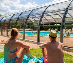 Panorama de personnes au solarium avec vue sur la piscine couverte du Clos de la Chaume un camping Piscine Couverte dans les Vosges